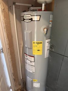 A.O. Smith ProLine water heater with an EnergyGuide label, installed in a narrow utility closet beside an HVAC unit